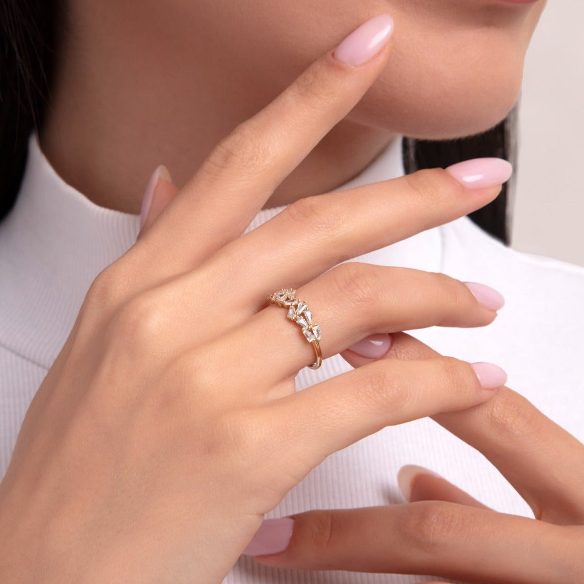 Close-up of a woman wearing an asymmetric baguette diamond ring on her finger in 14K yellow gold