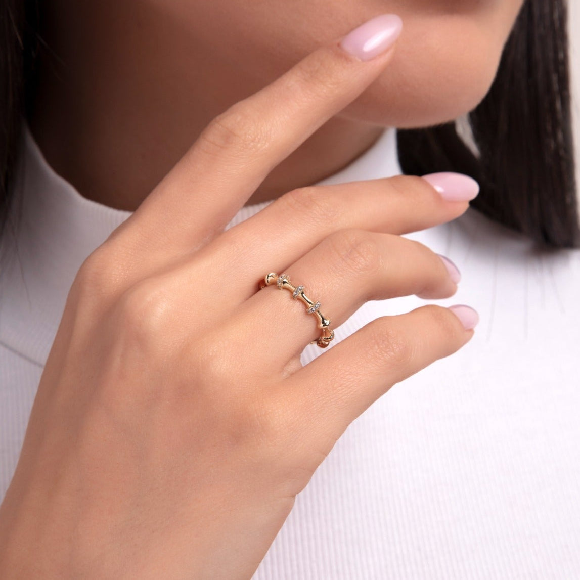Close-up of a woman's hand wearing a 14K gold chain-style ring with baguette-cut stones, styled in a contemporary and geometric design.
