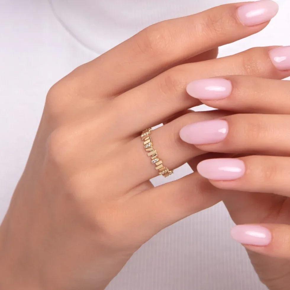 Close-up of a woman's hand wearing a 14K gold eternity band with baguette-cut cubic zirconia