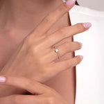 Close-up of a woman's hand wearing a 14K gold opal baguette ring with dainty band