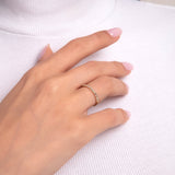 Close-up of a woman's hand wearing a 14K gold band with alternating baguette and round-cut diamonds