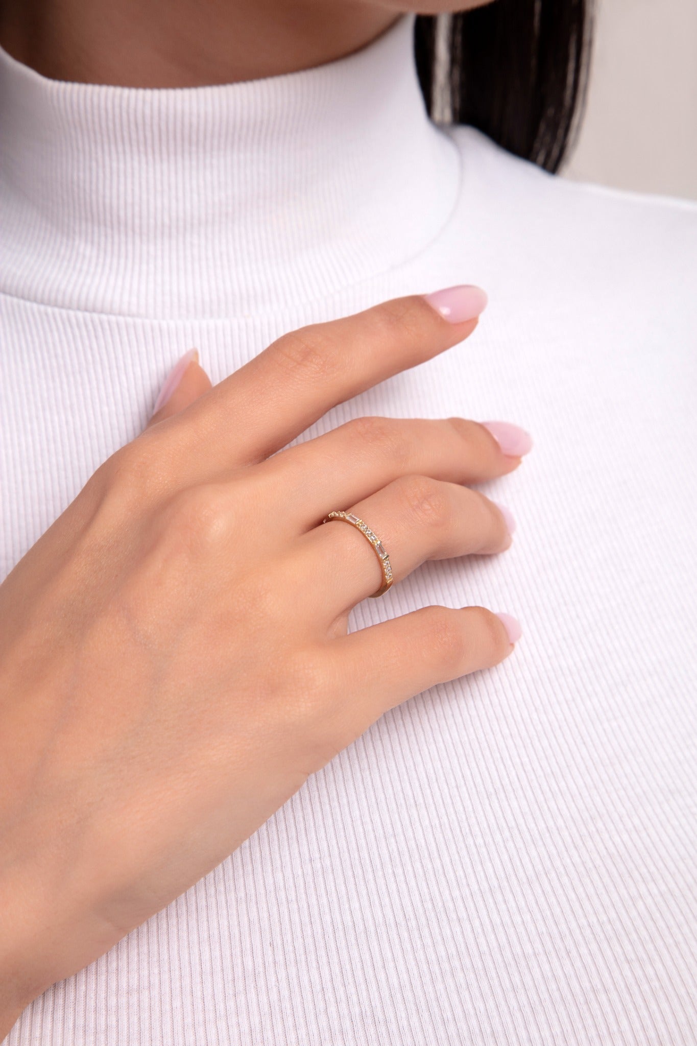 Close-up of a woman's hand wearing a 14K gold band with alternating baguette and round-cut diamonds