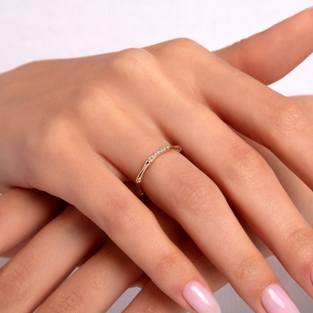 Close-up of a woman’s hand wearing a 14K gold bamboo-style ring with small diamond accents