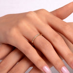 Close-up of a woman’s hand wearing a 14K gold bamboo-style ring with small diamond accents
