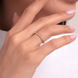 Woman wearing a 14K gold ring with polished beaded texture, delicate minimalist style