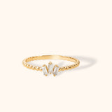 Minimal 14K gold ring with beaded band and three baguette-cut zircon stones in a clustered center design