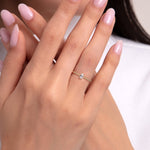Close-up of a woman’s hand wearing a delicate solitaire ring with a beaded gold band – elegant and dainty design