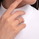 Minimalist bezel solitaire ring worn on finger, with 14K gold dainty band and round center stone