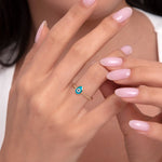 Woman wearing a 14K gold teardrop-shaped blue evil eye ring with a fine beaded band