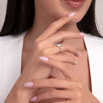 Model's hand with a 14K gold ring featuring a rectangular blue topaz stone, elegantly styled with soft pink nails.