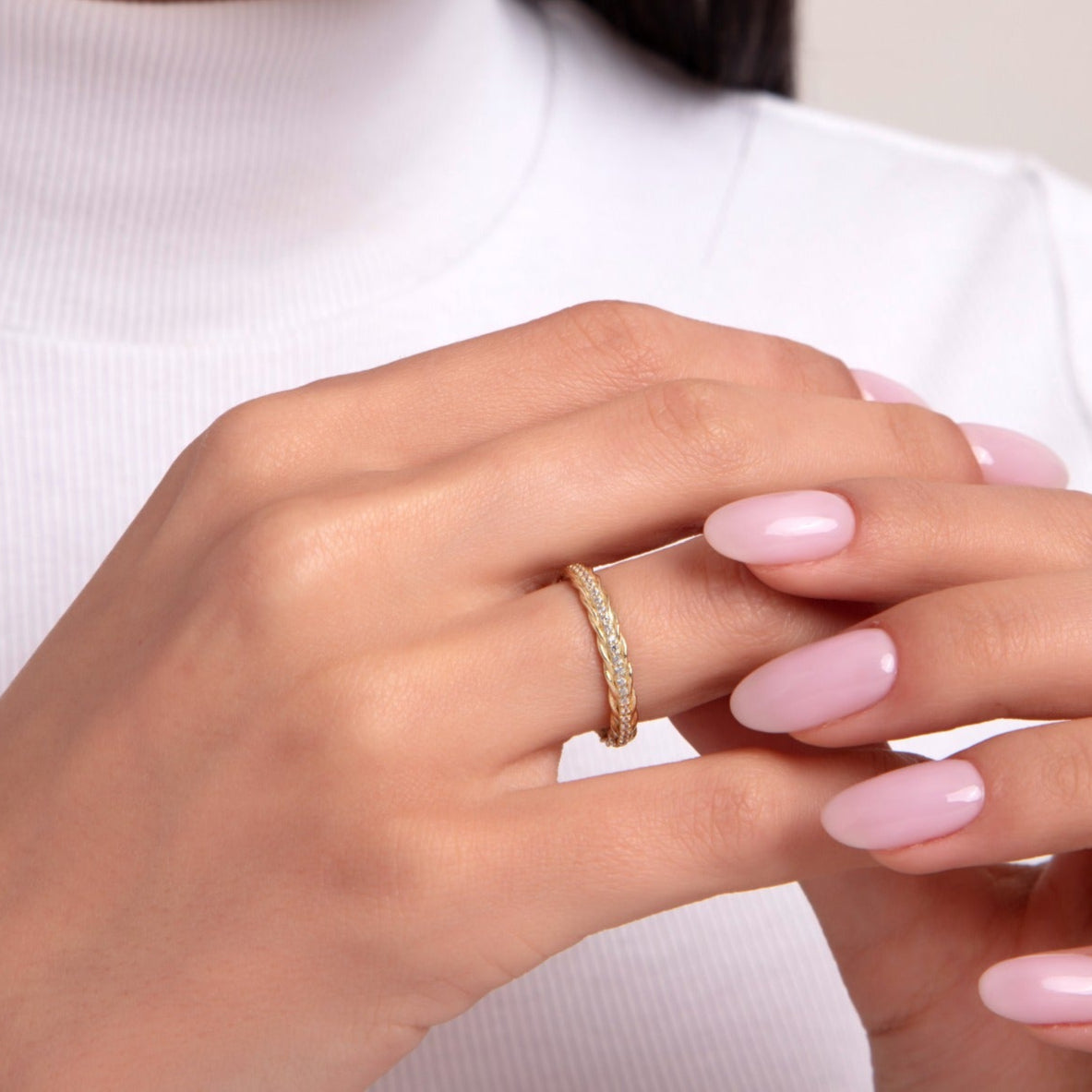 Close-up of a woman wearing a 14K gold braided diamond ring with rope design