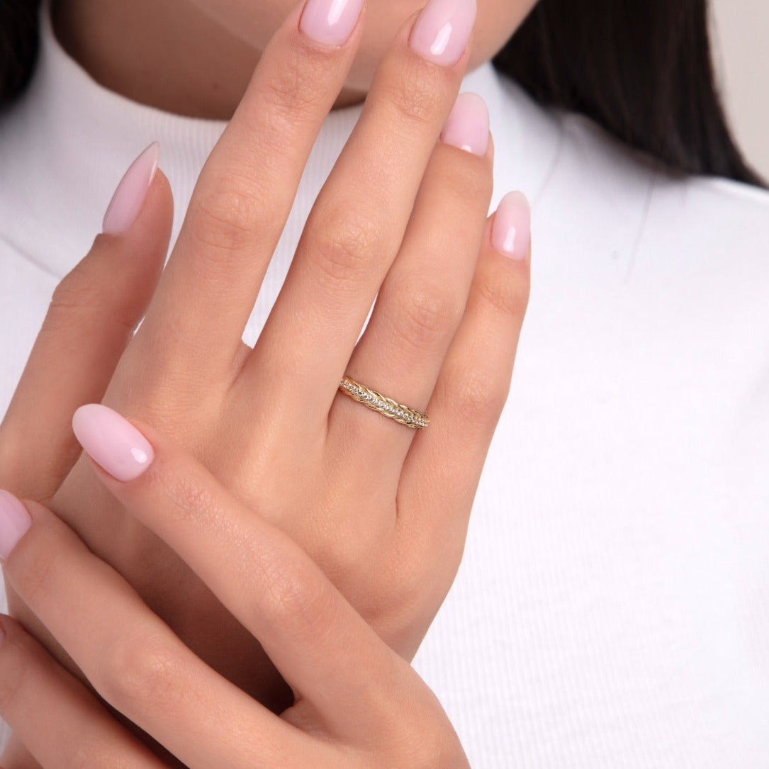 Elegant braided 14K gold ring with diamond accents, worn on a woman's finger