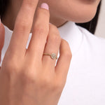 A 14K gold chain-textured ring featuring a cushion-cut center stone surrounded by a halo of smaller diamonds, shown on a hand with soft pink nails.