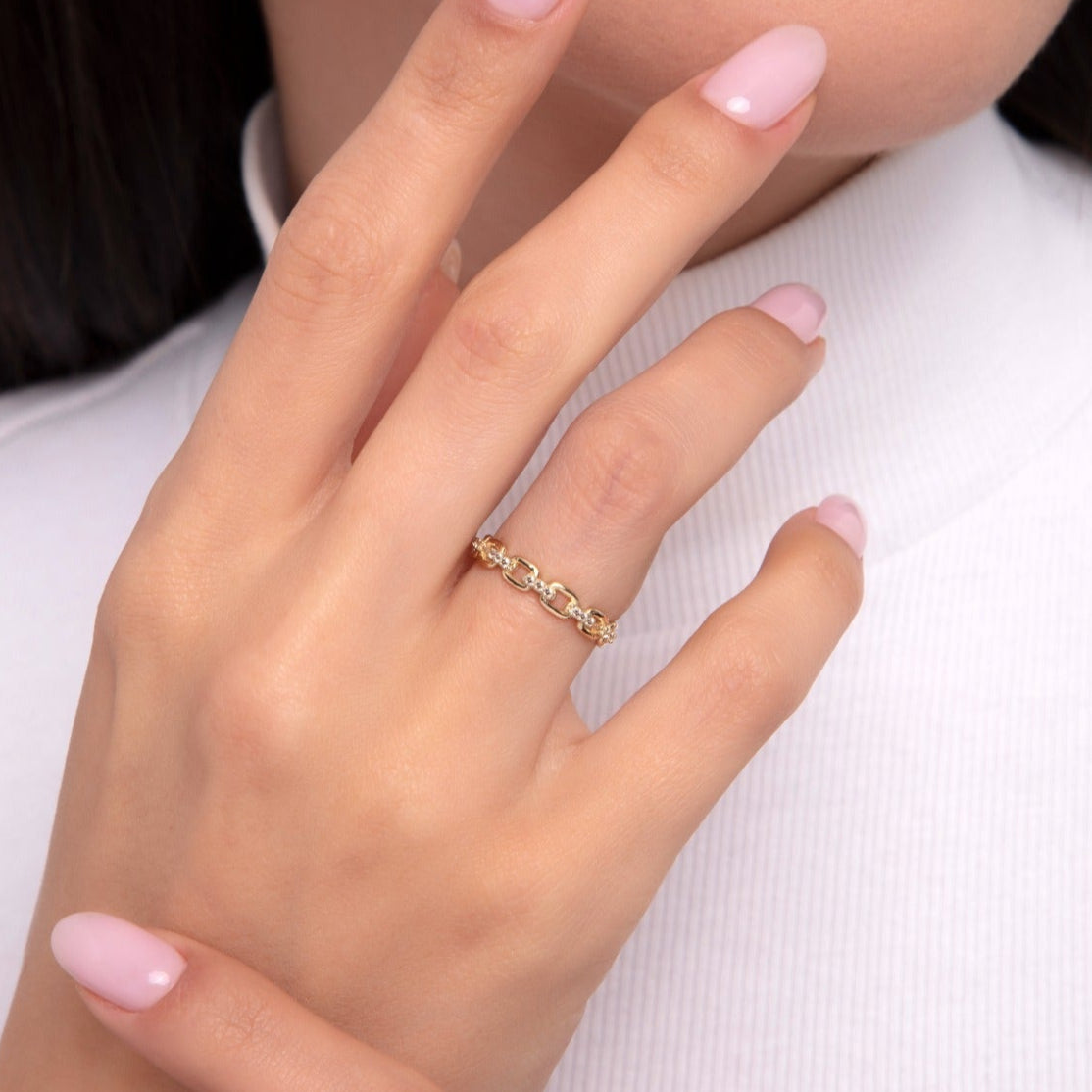Woman wearing a 14K gold chain link ring with sparkling zircon details