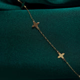 Minimalist 14K gold bracelet featuring clover charms – symbolic lucky charm design on rich green satin fabric.