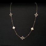 14K gold necklace with alternating solid and open clover charms on a delicate chain