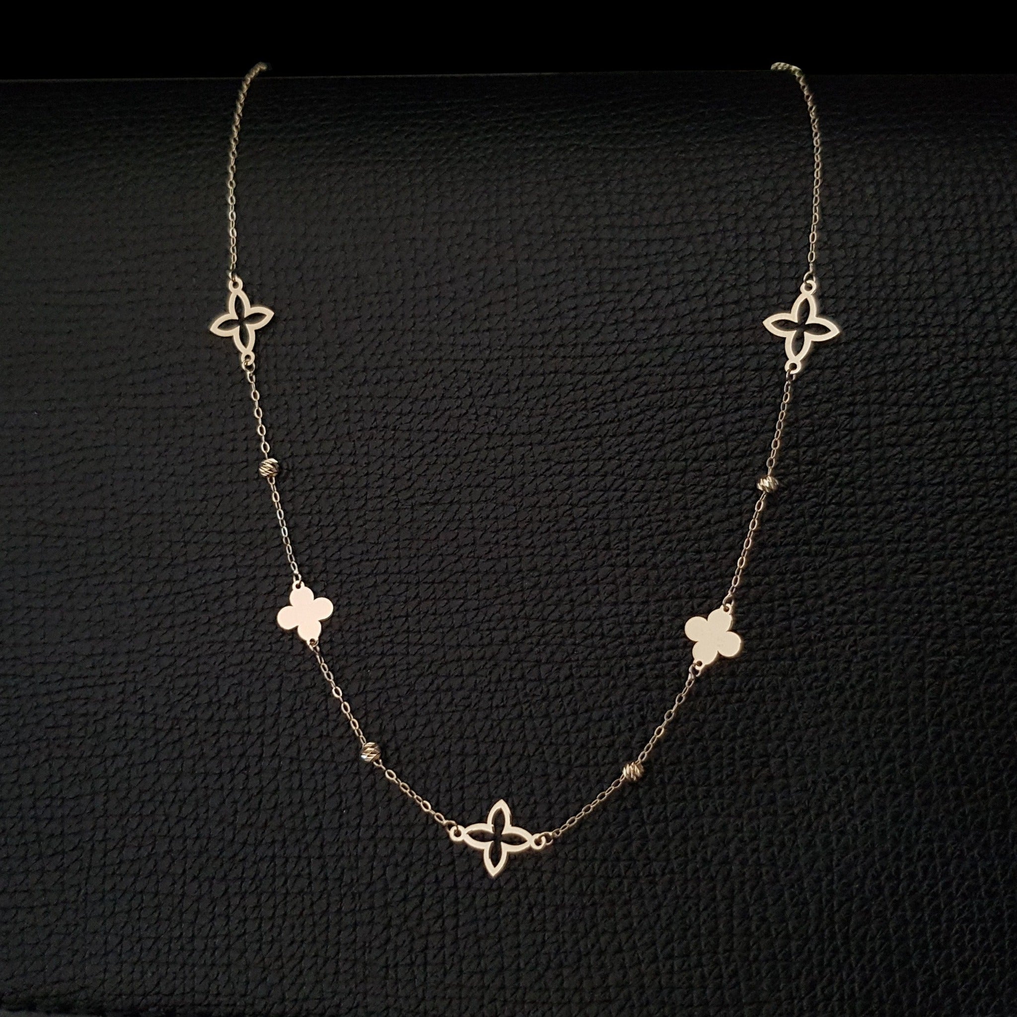 14K gold necklace with alternating solid and open clover charms on a delicate chain
