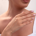 Model wearing a 14k gold cross hand chain bracelet across the wrist and finger

