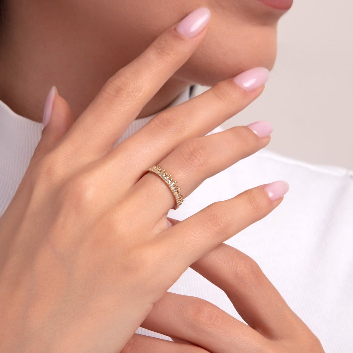 Woman wearing a crown-style 14K gold eternity ring with white stones and bead detailing