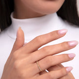 Close-up of a woman wearing a dainty 14K gold ring with a gentle wave shape and small diamond accents