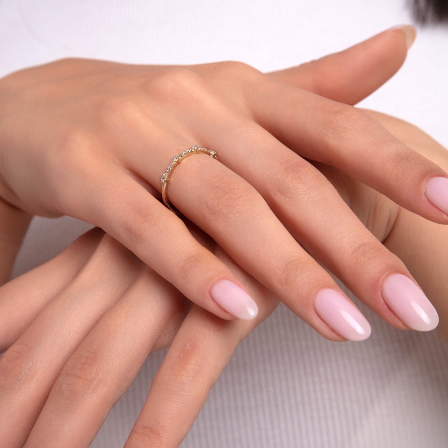 Woman’s hand wearing 14K gold curved diamond ring – delicate stacking band for minimalist jewelry lovers