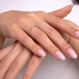 Woman’s hand wearing 14K gold curved diamond ring – delicate stacking band for minimalist jewelry lovers