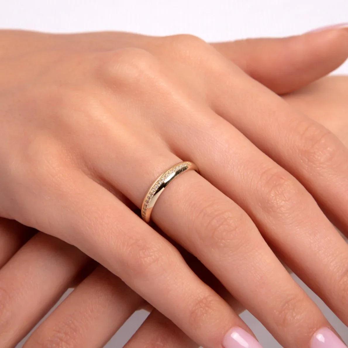 Close-up of a woman's hand wearing a slim 14K gold diamond-cut textured ring