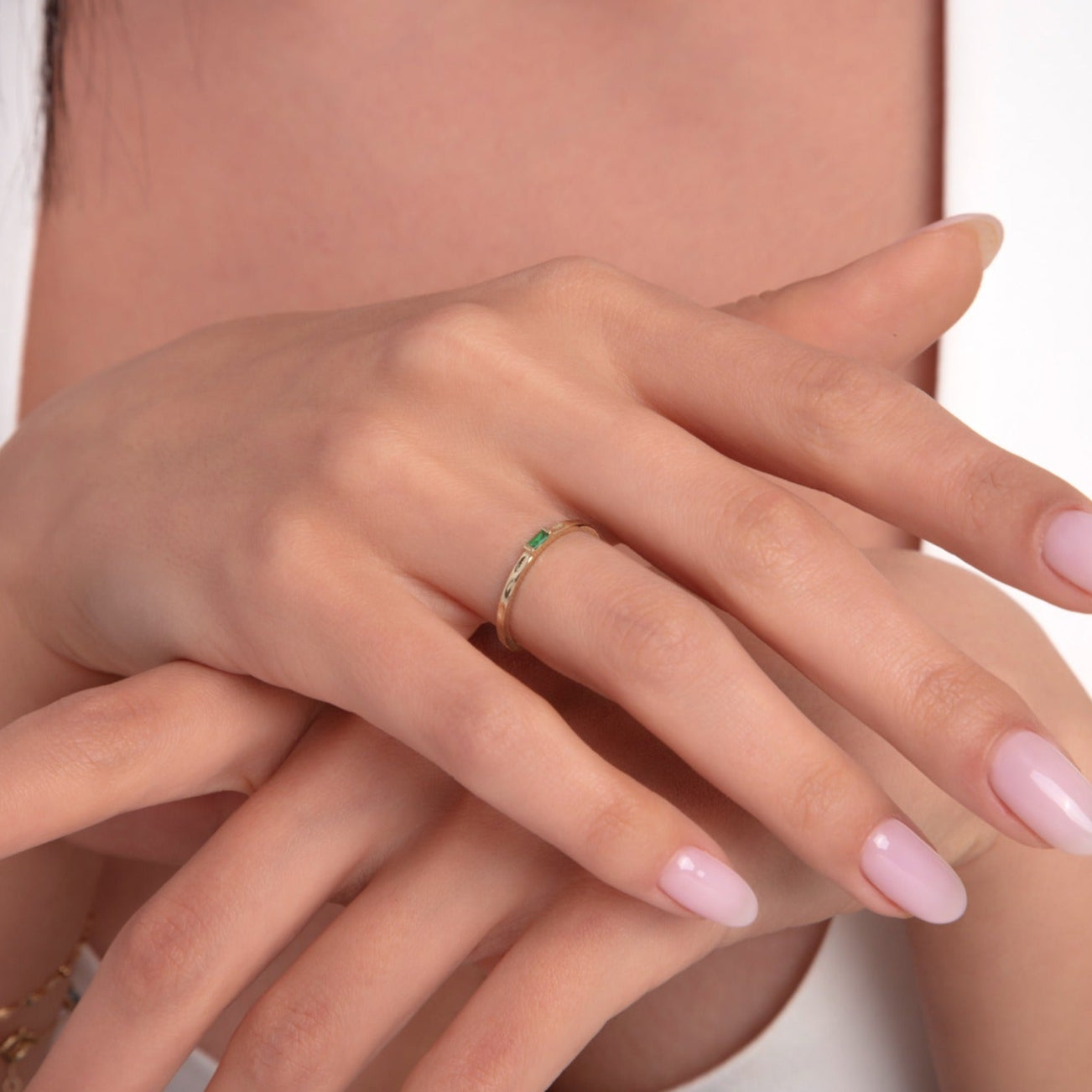 14K gold minimalist ring with emerald baguette stone on woman's hand