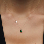 14K gold necklace with emerald teardrop pendant and butterfly charm worn on model’s neck