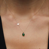 14K gold necklace with emerald teardrop pendant and butterfly charm worn on model’s neck