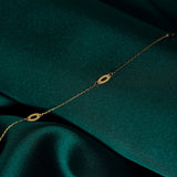 14K gold bracelet with elongated marquise-shaped link elements, displayed elegantly on green satin background.