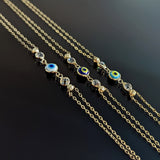 Three 14K gold evil eye bracelets with colorful charms and gemstone accents on black background