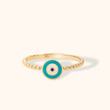 14K gold turquoise evil eye ring with round enamel charm and beaded band on neutral background.
