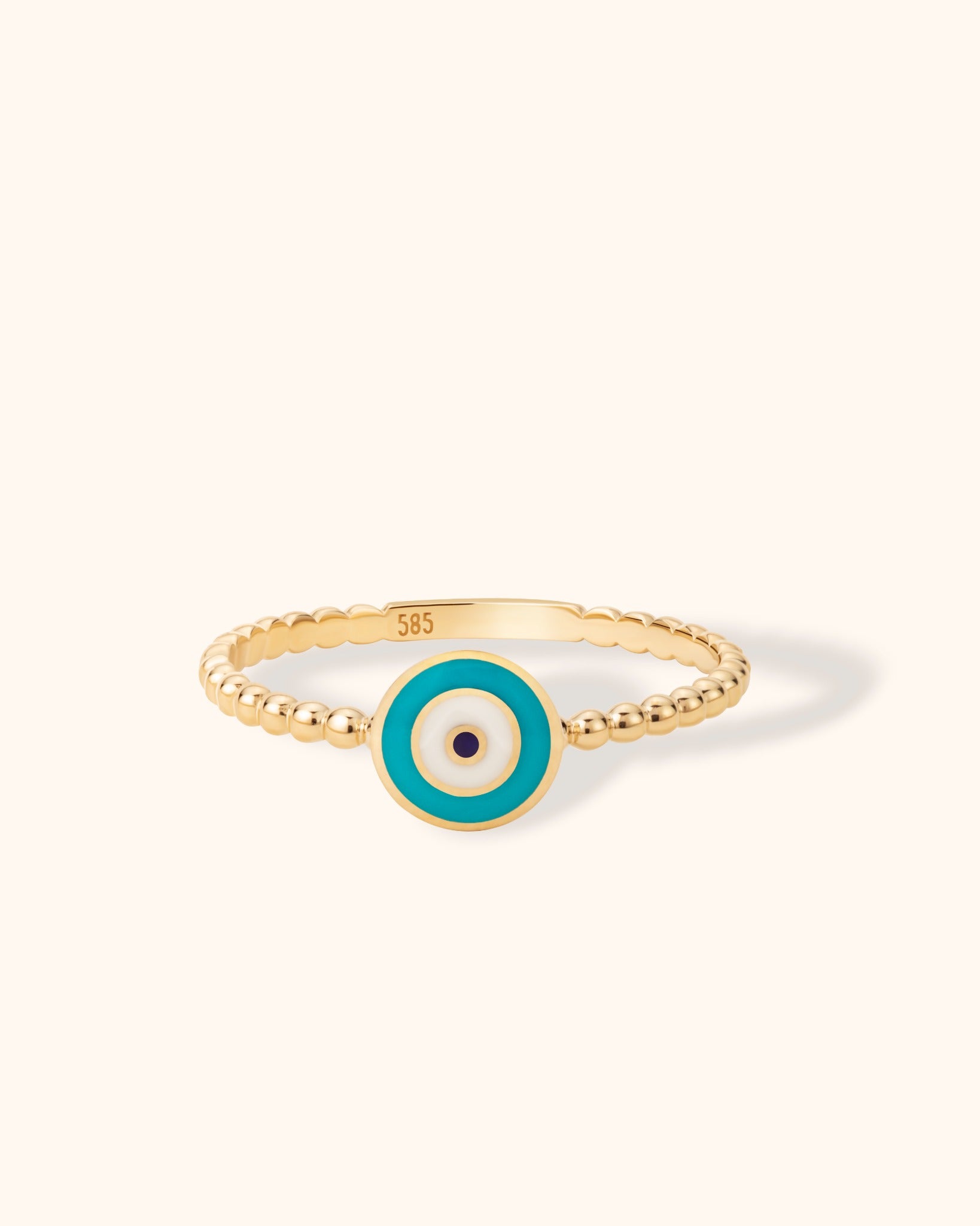 14K gold turquoise evil eye ring with round enamel charm and beaded band on neutral background.