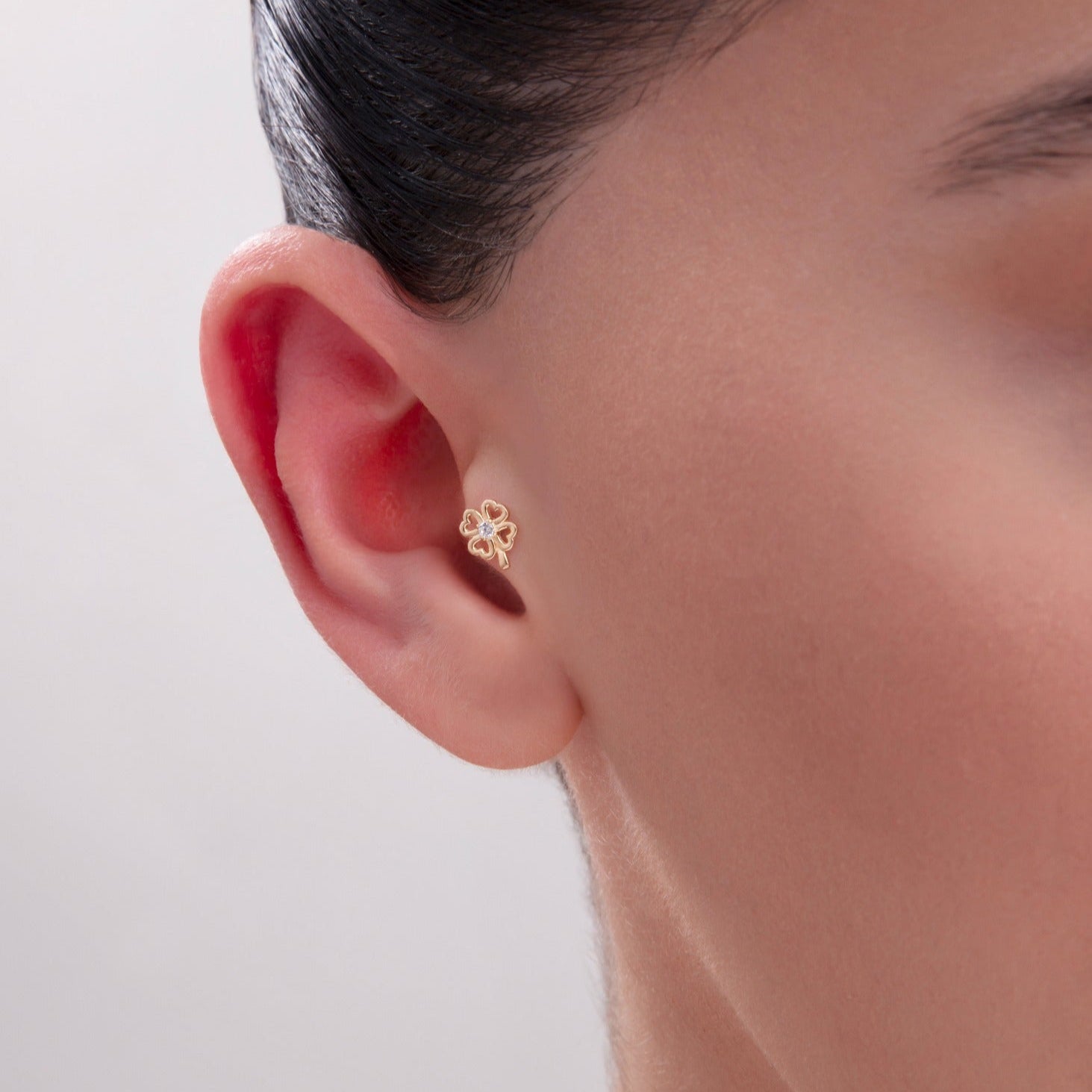 Model wearing a 14K Gold Four-Leaf Clover Tragus Stud with center CZ stone – A dainty and symbolic cartilage earring representing luck and positivity, perfect for tragus or helix piercings