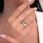 Woman wearing a bold geometric ring in 14K gold with black enamel sections and diamond pavé detail