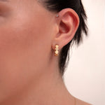 Close-up of a woman wearing 14k gold hexagon block hoop earrings

