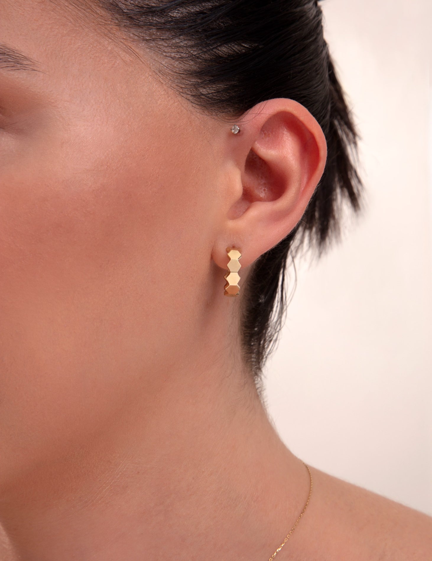 Close-up of a woman wearing 14k gold hexagon block hoop earrings


