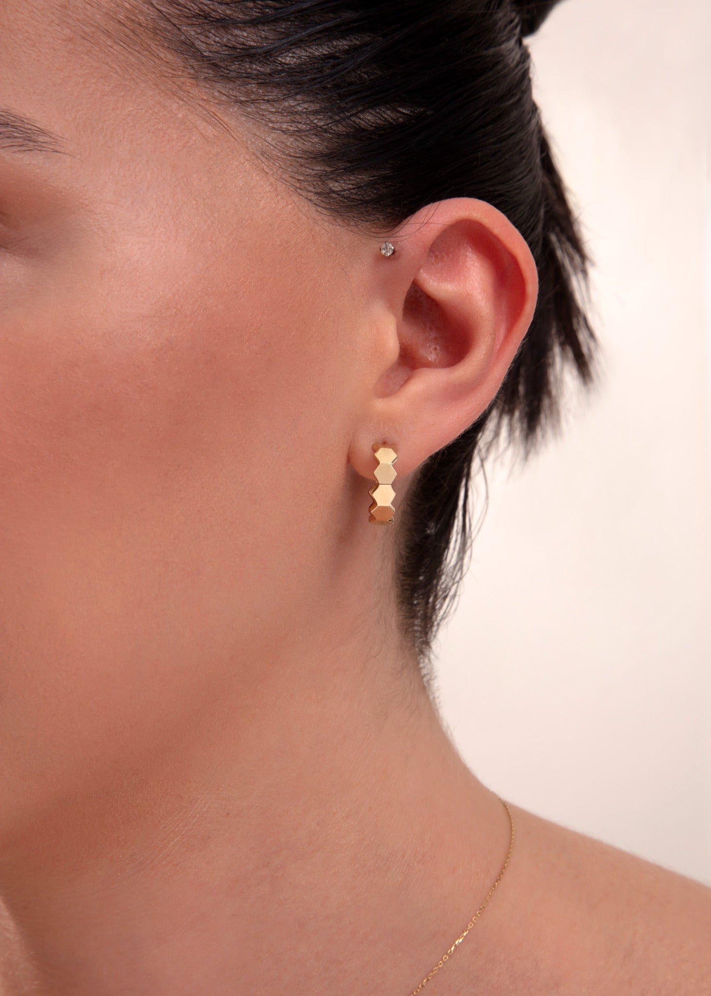 Close-up of a woman wearing 14k gold hexagon block hoop earrings


