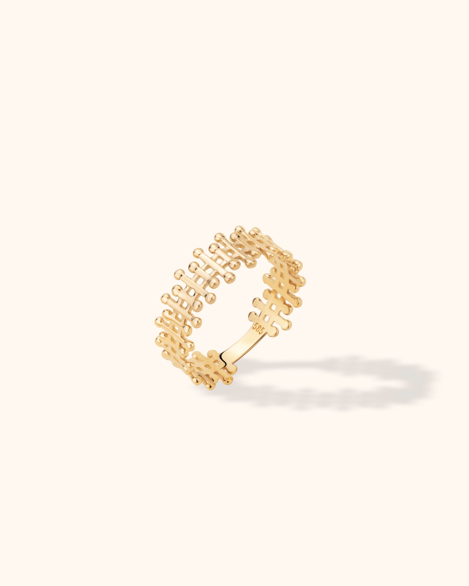 Modern 14k gold ring with openwork geometric lace pattern on a neutral background


