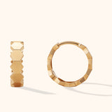 Minimalist 14k gold hoop earrings with hexagon facets on cream background

