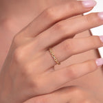 Close-up of a woman's hand wearing a 14K gold ring with infinity symbols and small stone accents.
