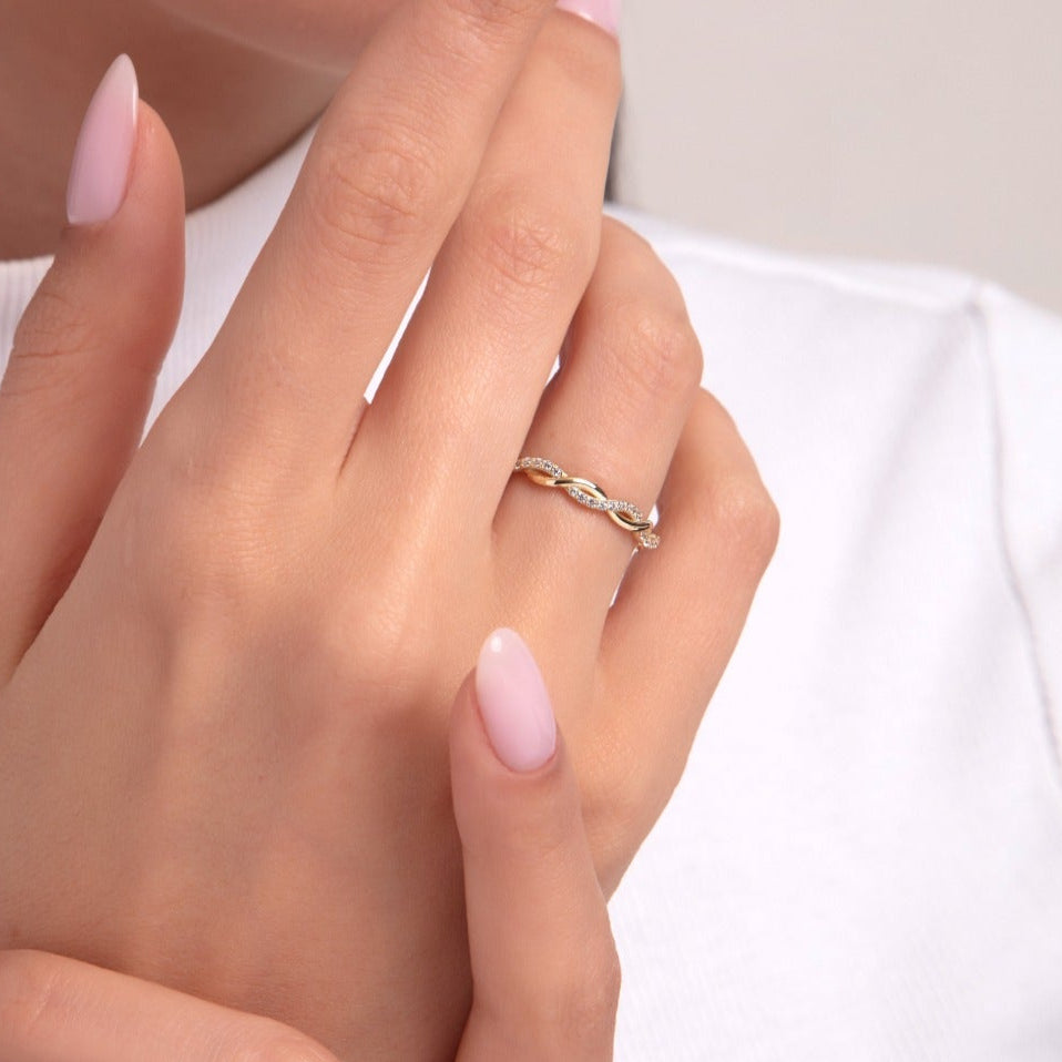 Elegant woman wearing a 14K gold ring with twisted infinity design and zircon stones