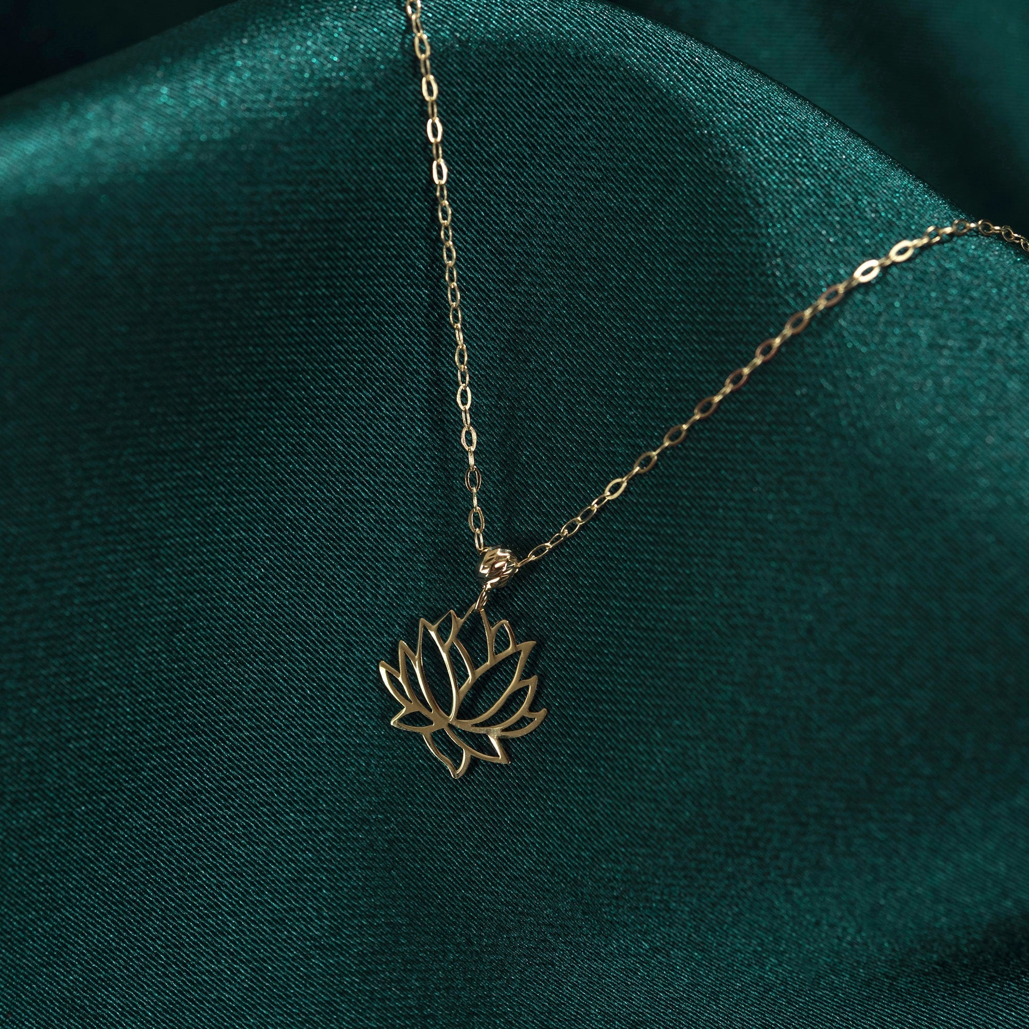14K real gold necklace with a minimalist lotus flower pendant displayed on dark green silk.