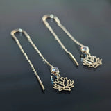 14K gold lotus threader earrings with crystal accents on black background, showcasing spiritual and elegant design
