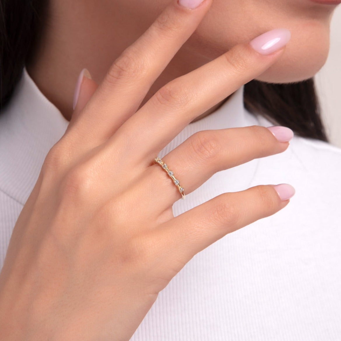 Close-up of a marquise-cut zirconia gold ring worn on model’s finger with soft pink nails