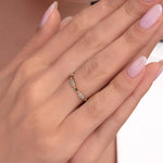 Close-up of a woman wearing a dainty 14K gold ring with alternating marquise diamonds and emerald accents.