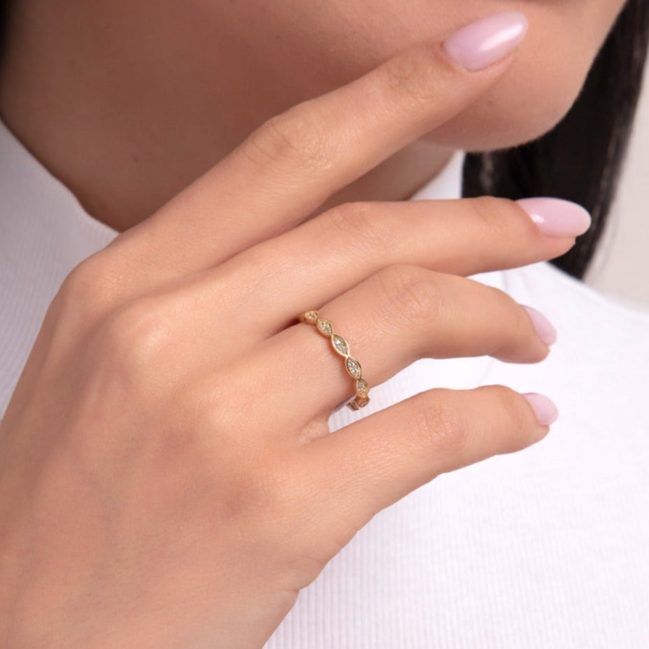 Close-up image of a woman wearing a 14K gold ring with alternating marquise and round cut diamond shapes, creating a delicate vintage-inspired design.