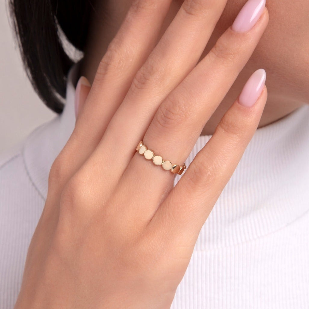 Woman wearing a 14K gold ring with a full band of matte-finished circular dots