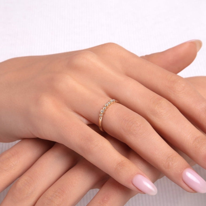 Model wearing a delicate 14K gold ring with small round diamonds on a thin band
